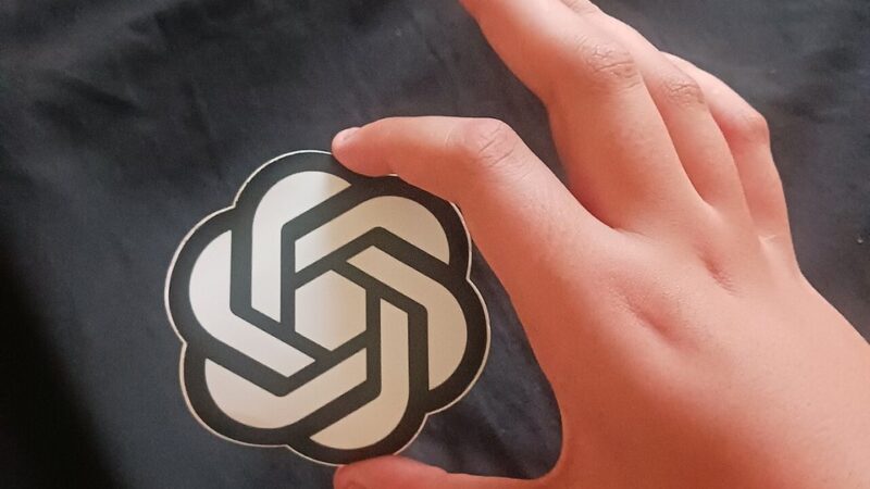 Hand holding an OpenAI sticker symbolising ChatGPT use