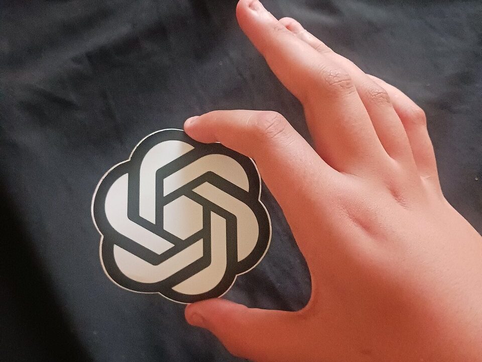 Hand holding an OpenAI sticker symbolising ChatGPT use