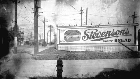 Historic roadside advertising billboard beside a street with tram lines