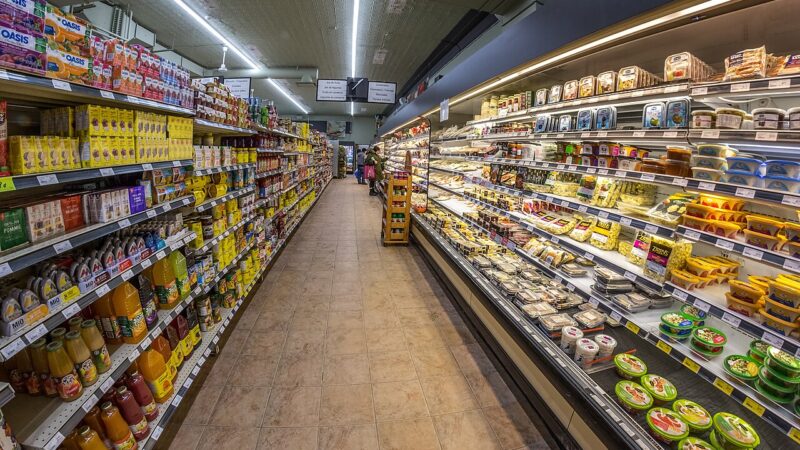 Long supermarket aisle with shelves of packaged food and drinks