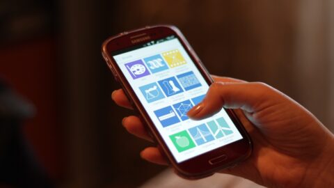 Hand holding a smartphone showing a grid of colourful app icons