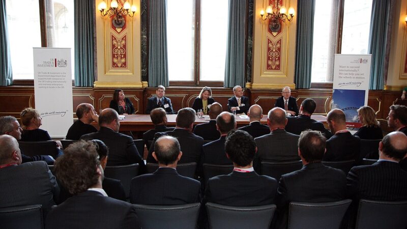 Business leaders seated around a table at a formal industry meeting