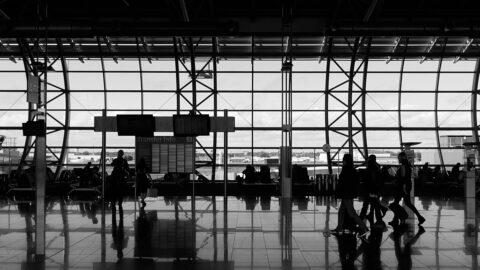 Travellers silhouetted against the glass wall of an airport terminal